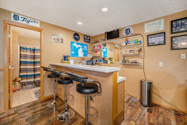 bar featuring dark wood-type flooring and a textured ceiling