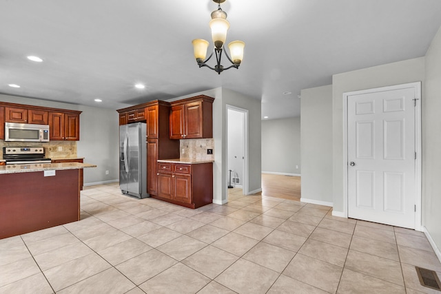 kitchen with light stone counters, appliances with stainless steel finishes, a notable chandelier, and tasteful backsplash