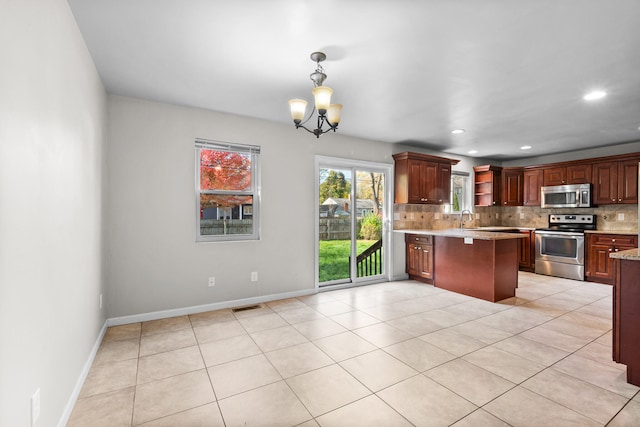 kitchen with tasteful backsplash, appliances with stainless steel finishes, sink, a notable chandelier, and decorative light fixtures