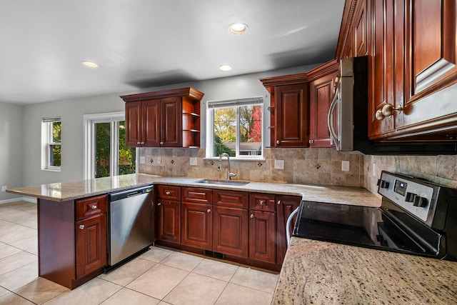 kitchen with kitchen peninsula, tasteful backsplash, light stone counters, appliances with stainless steel finishes, and sink