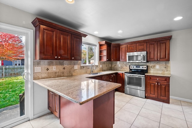 kitchen featuring kitchen peninsula, backsplash, sink, light tile patterned floors, and appliances with stainless steel finishes