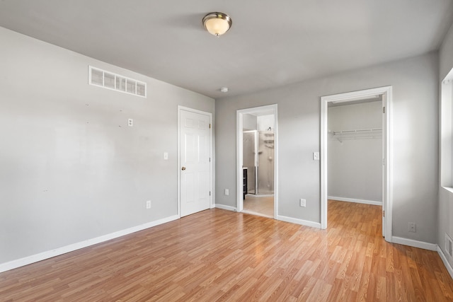 unfurnished bedroom featuring a closet, light hardwood / wood-style flooring, a spacious closet, and ensuite bathroom