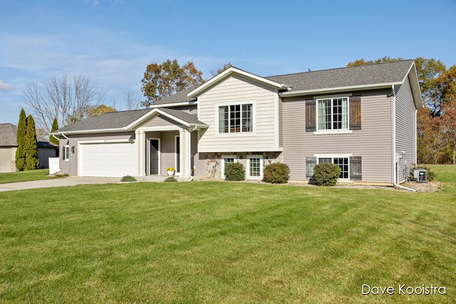 split level home with central AC unit, a garage, and a front yard