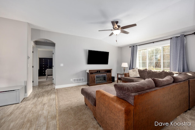 living room with ceiling fan, light wood-type flooring, and vaulted ceiling