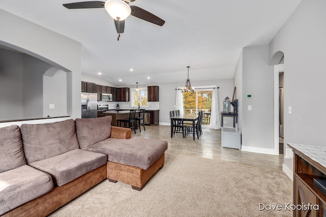 living room with ceiling fan with notable chandelier, light colored carpet, and sink