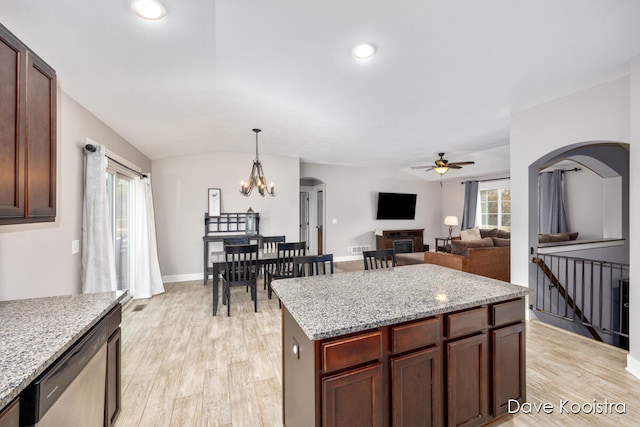 kitchen featuring a kitchen island, pendant lighting, light stone countertops, light hardwood / wood-style floors, and ceiling fan with notable chandelier