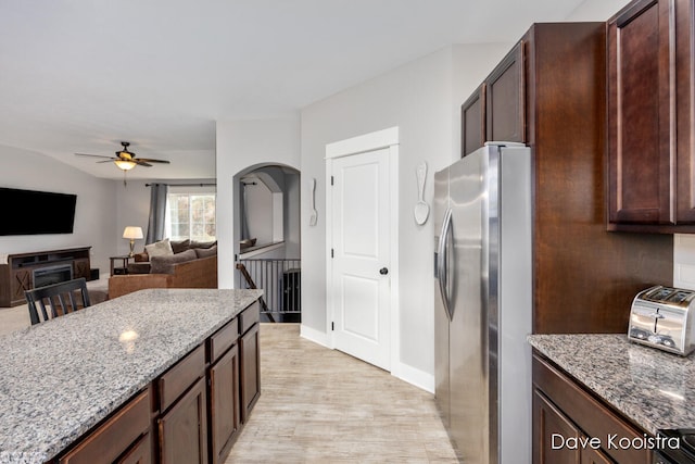 kitchen featuring dark brown cabinets, light hardwood / wood-style floors, stainless steel fridge with ice dispenser, and light stone countertops