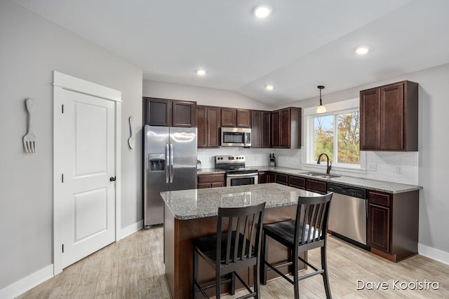 kitchen with stainless steel appliances, sink, decorative light fixtures, lofted ceiling, and a center island