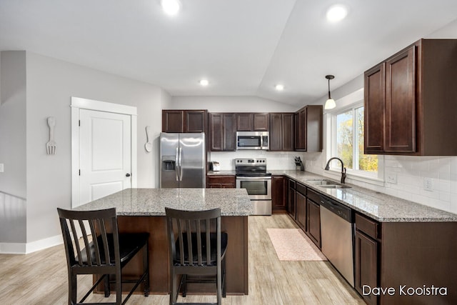 kitchen featuring light hardwood / wood-style floors, lofted ceiling, hanging light fixtures, sink, and appliances with stainless steel finishes