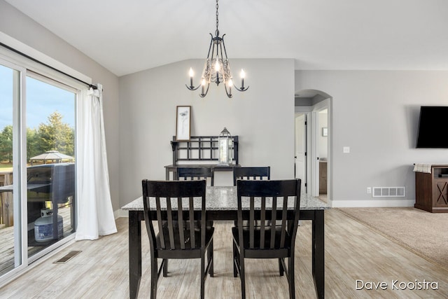 dining space with light hardwood / wood-style floors, a chandelier, and vaulted ceiling