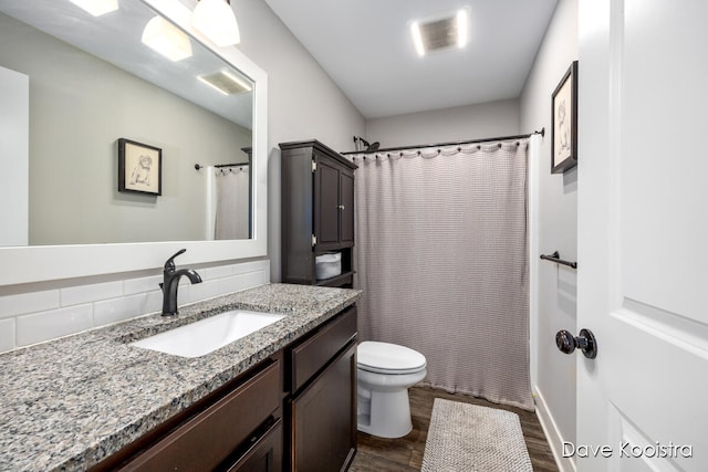 bathroom with toilet, curtained shower, hardwood / wood-style flooring, tasteful backsplash, and vanity