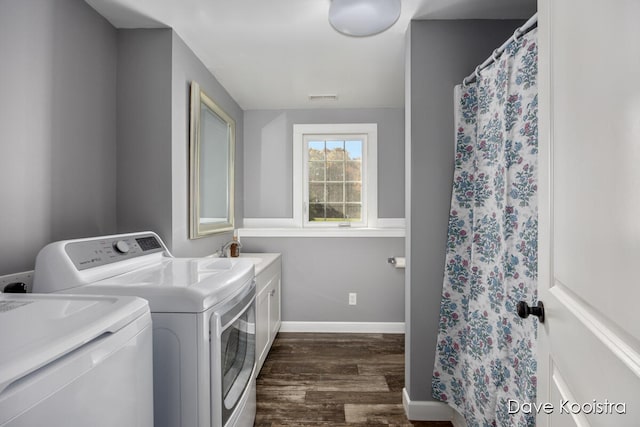 washroom featuring dark hardwood / wood-style flooring, cabinets, and washer and clothes dryer