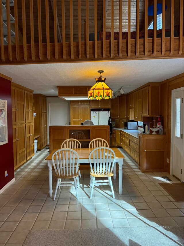 dining space featuring a textured ceiling and light tile patterned floors