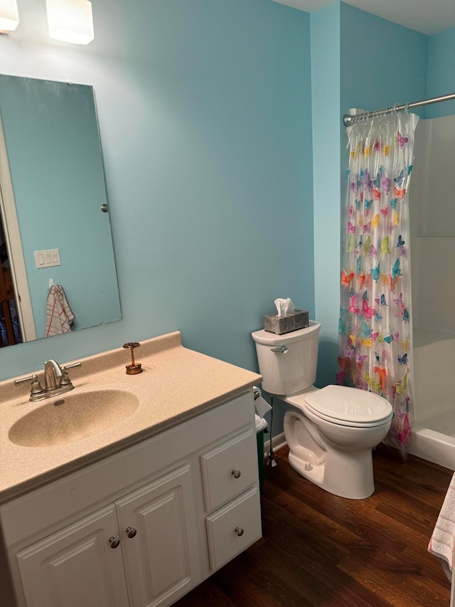 bathroom featuring toilet, hardwood / wood-style floors, a shower with curtain, and vanity