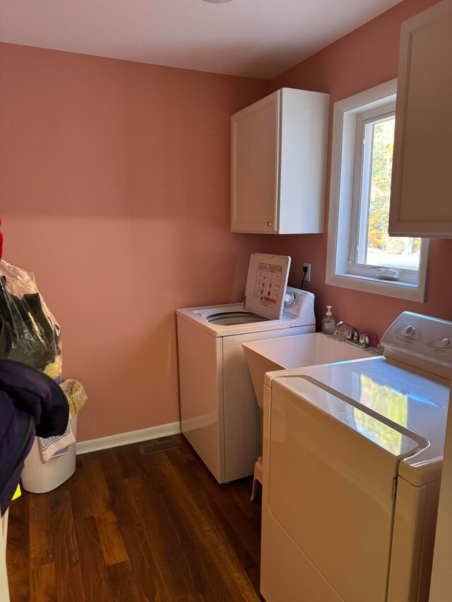 laundry area featuring cabinets, independent washer and dryer, and dark hardwood / wood-style flooring