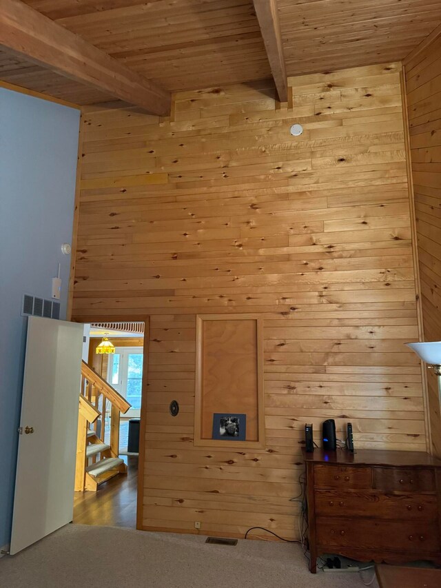 unfurnished bedroom featuring wood ceiling, wood walls, beamed ceiling, and carpet flooring