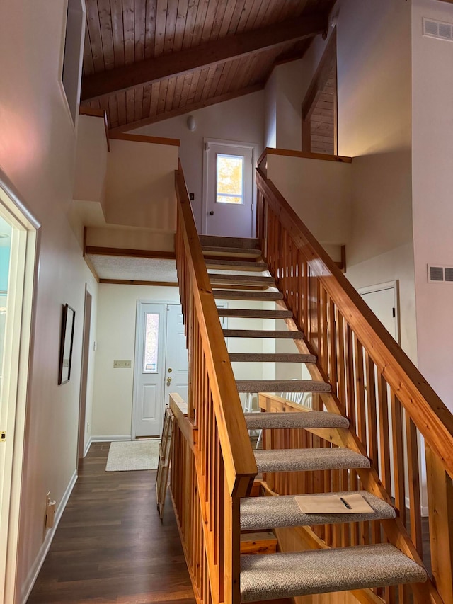 stairs featuring beam ceiling, wooden ceiling, wood-type flooring, and plenty of natural light