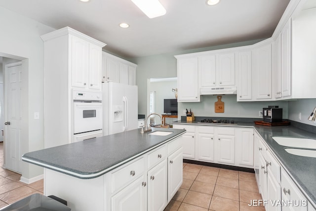 kitchen featuring white appliances, light tile patterned flooring, sink, and white cabinets