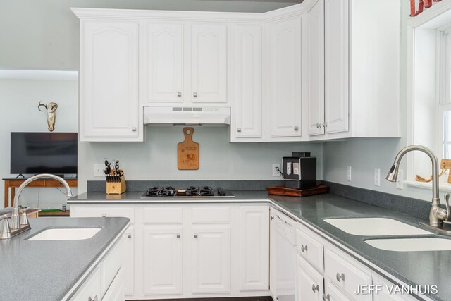 kitchen with black gas stovetop, white cabinetry, sink, and range hood