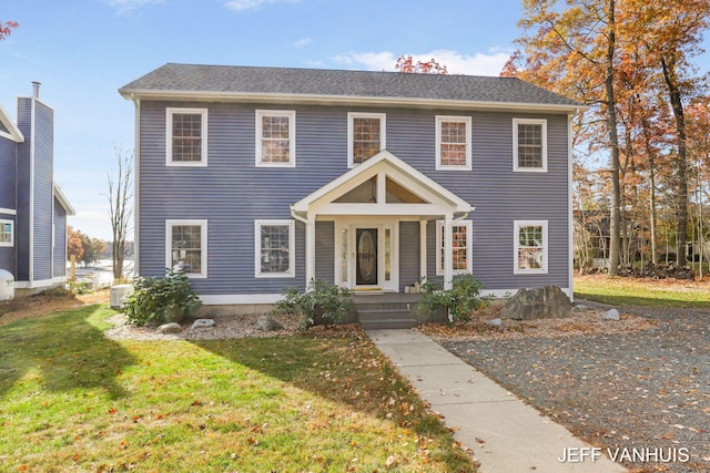 colonial house featuring central air condition unit and a front yard