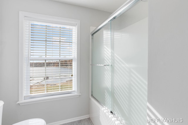 bathroom with toilet, enclosed tub / shower combo, and plenty of natural light