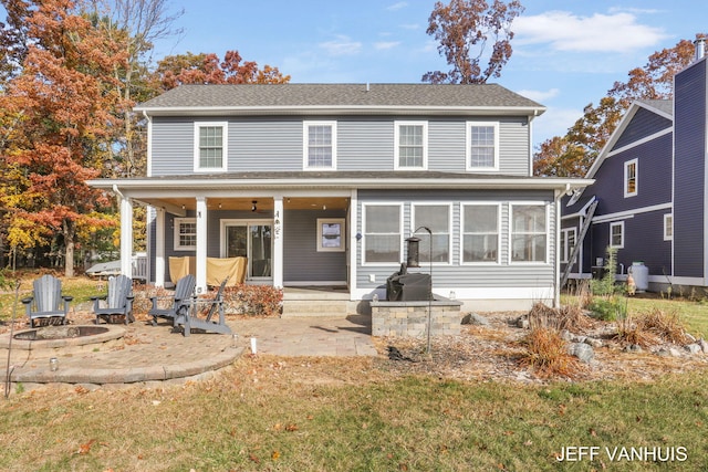 view of front of house featuring ceiling fan, a sunroom, an outdoor fire pit, a patio, and a front lawn