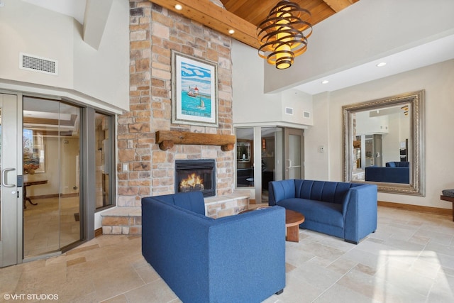 living room with a high ceiling, wooden ceiling, a stone fireplace, and a notable chandelier