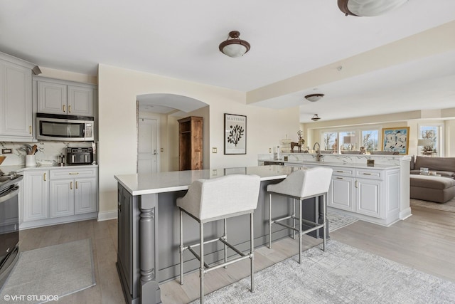 kitchen with a center island, a kitchen breakfast bar, backsplash, kitchen peninsula, and light wood-type flooring