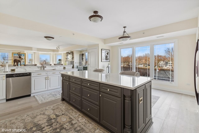 kitchen featuring dishwasher, sink, pendant lighting, light hardwood / wood-style floors, and a kitchen island