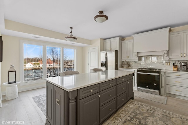 kitchen featuring pendant lighting, decorative backsplash, light wood-type flooring, appliances with stainless steel finishes, and a kitchen island