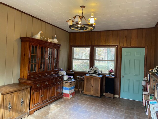 dining space with a notable chandelier and wooden walls