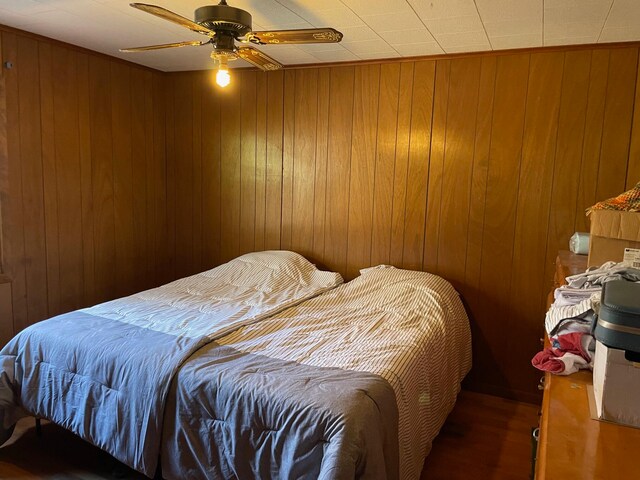 bedroom featuring wooden walls and ceiling fan