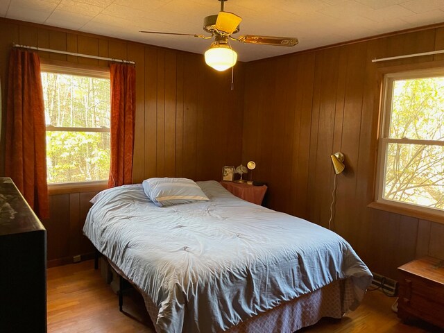 bedroom featuring multiple windows and wooden walls