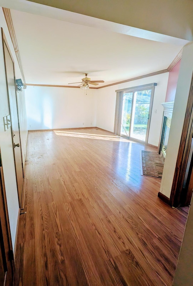 unfurnished living room with hardwood / wood-style floors, crown molding, and ceiling fan