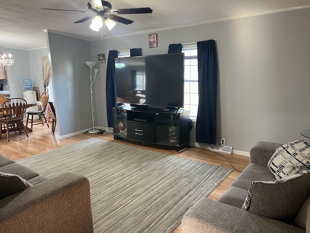 living room with light hardwood / wood-style floors, crown molding, a textured ceiling, and ceiling fan with notable chandelier