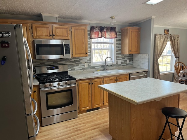 kitchen featuring a healthy amount of sunlight, appliances with stainless steel finishes, sink, and a kitchen island