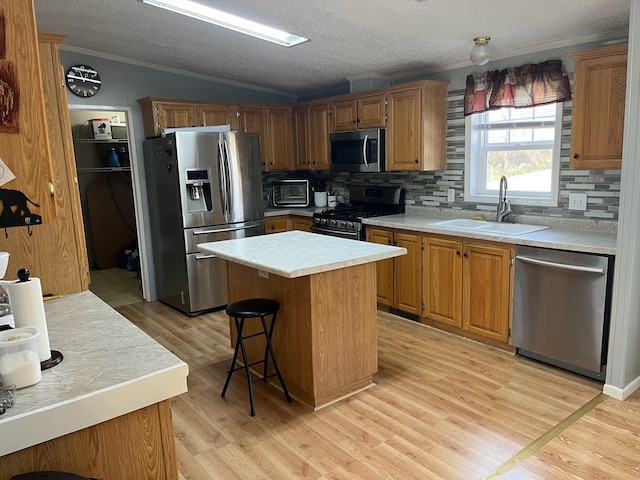 kitchen featuring lofted ceiling, sink, a center island, light wood-type flooring, and appliances with stainless steel finishes