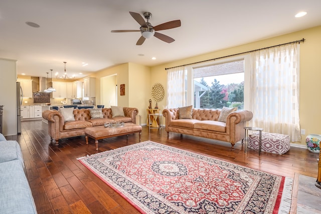 living room featuring ceiling fan with notable chandelier and dark hardwood / wood-style floors