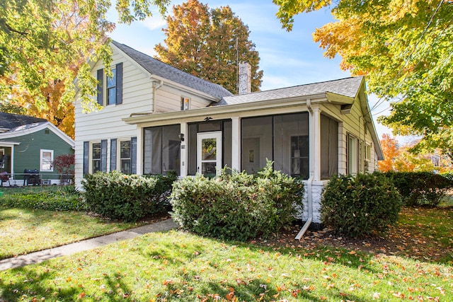 view of front facade with a front yard and a sunroom