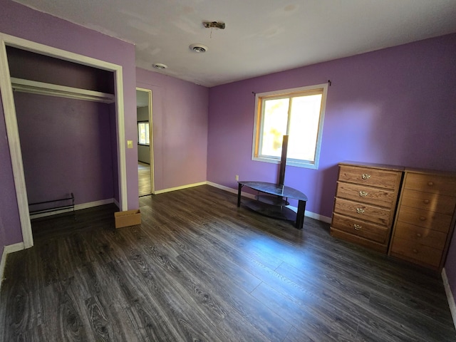 unfurnished bedroom featuring a closet, a baseboard heating unit, and dark hardwood / wood-style floors