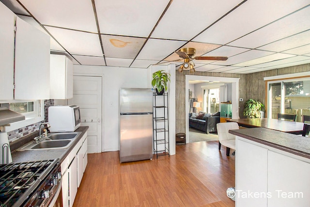 kitchen with sink, light wood-type flooring, ceiling fan, stainless steel appliances, and white cabinets