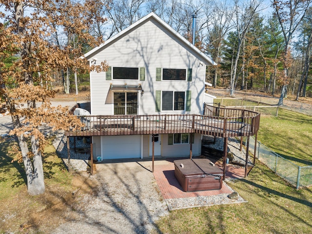 back of property with a deck, a yard, and a garage