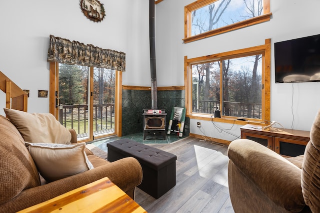 living room with a towering ceiling, wood-type flooring, and a wood stove