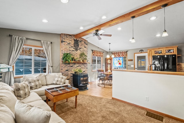 living room featuring sink, light tile patterned flooring, lofted ceiling with beams, a wood stove, and ceiling fan