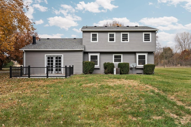 rear view of house with central air condition unit and a lawn