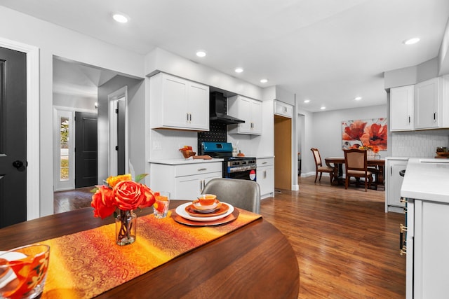 kitchen featuring wall chimney exhaust hood, white cabinets, stainless steel stove, and dark hardwood / wood-style flooring