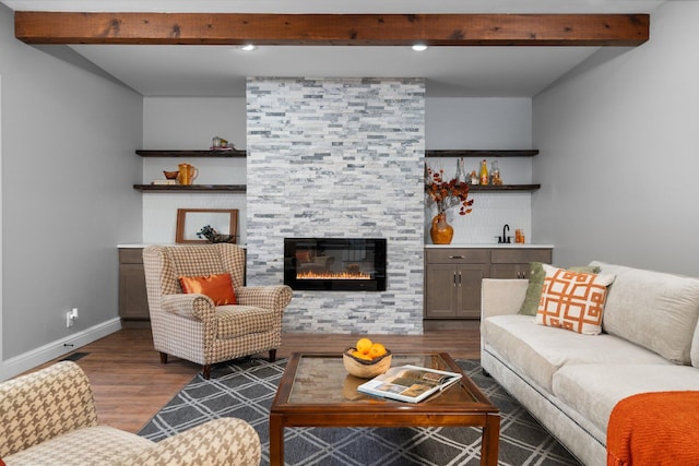 living room featuring beamed ceiling, dark wood-type flooring, and a fireplace