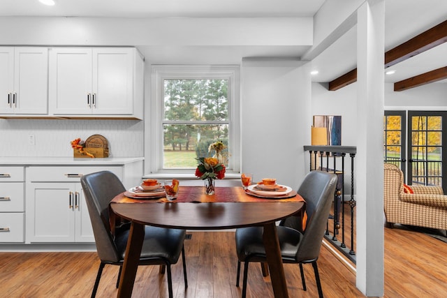 dining area with light hardwood / wood-style floors and beam ceiling