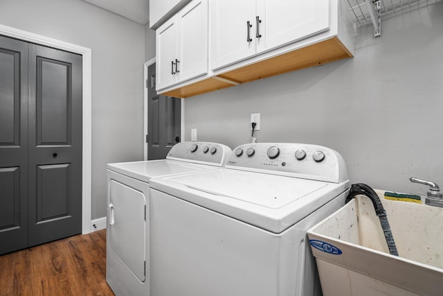 clothes washing area with sink, washer and dryer, cabinets, and dark hardwood / wood-style floors