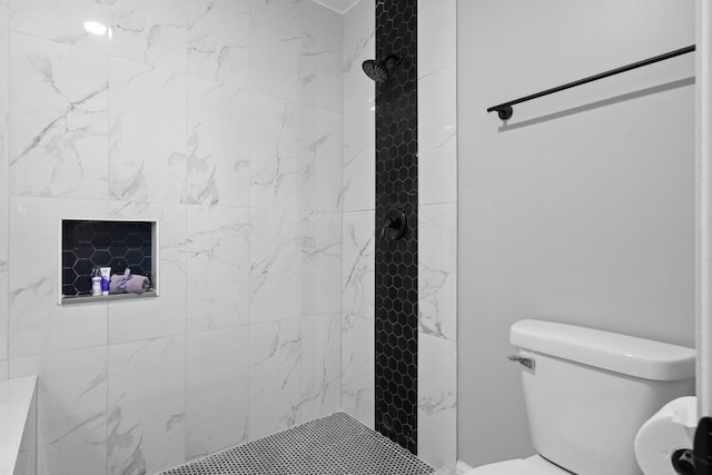 bathroom with a tile shower and toilet